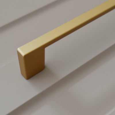 Metal furniture handle, matt gold color, with a unique textured surface
