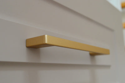 Metal furniture handle, matt gold color, with a unique textured surface