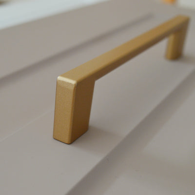 Metal furniture handle, matt gold color, with a unique textured surface