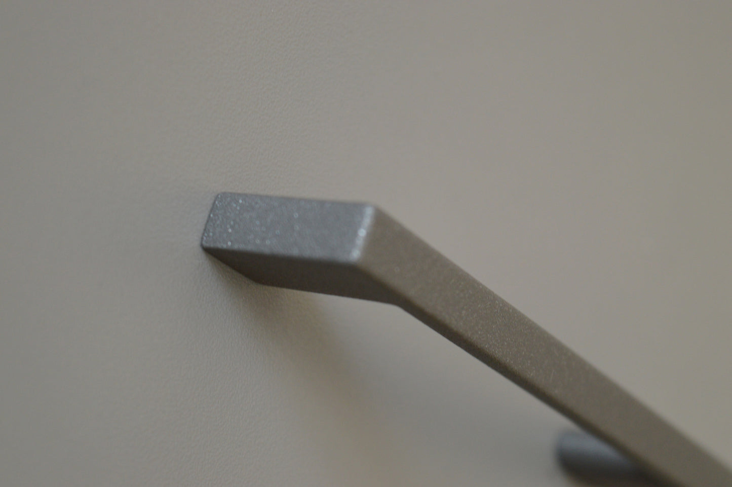 Metal furniture handle, anthracite gray color, with a unique textured surface
