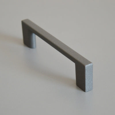Metal furniture handle, anthracite gray color, with a unique textured surface