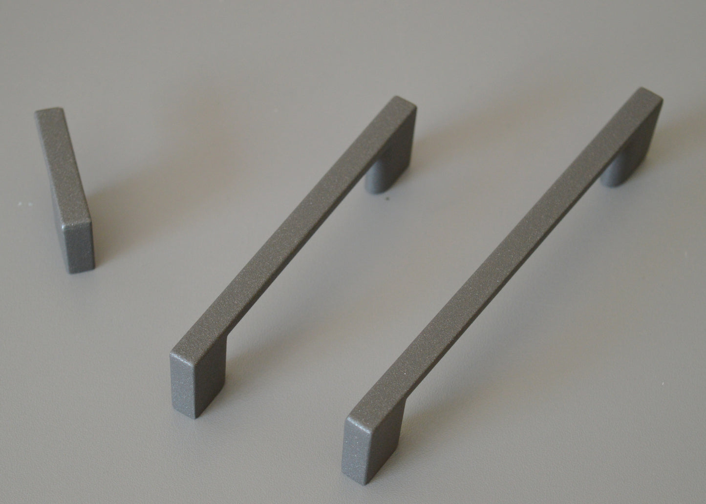 Metal furniture handle, anthracite gray color, with a unique textured surface