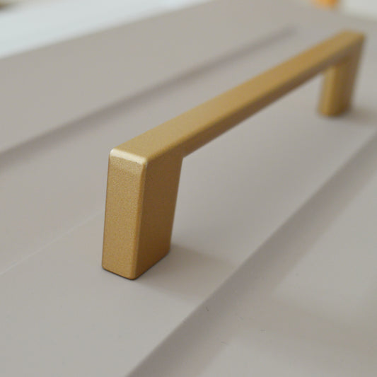 Metal furniture handle, matt gold color, with a unique textured surface