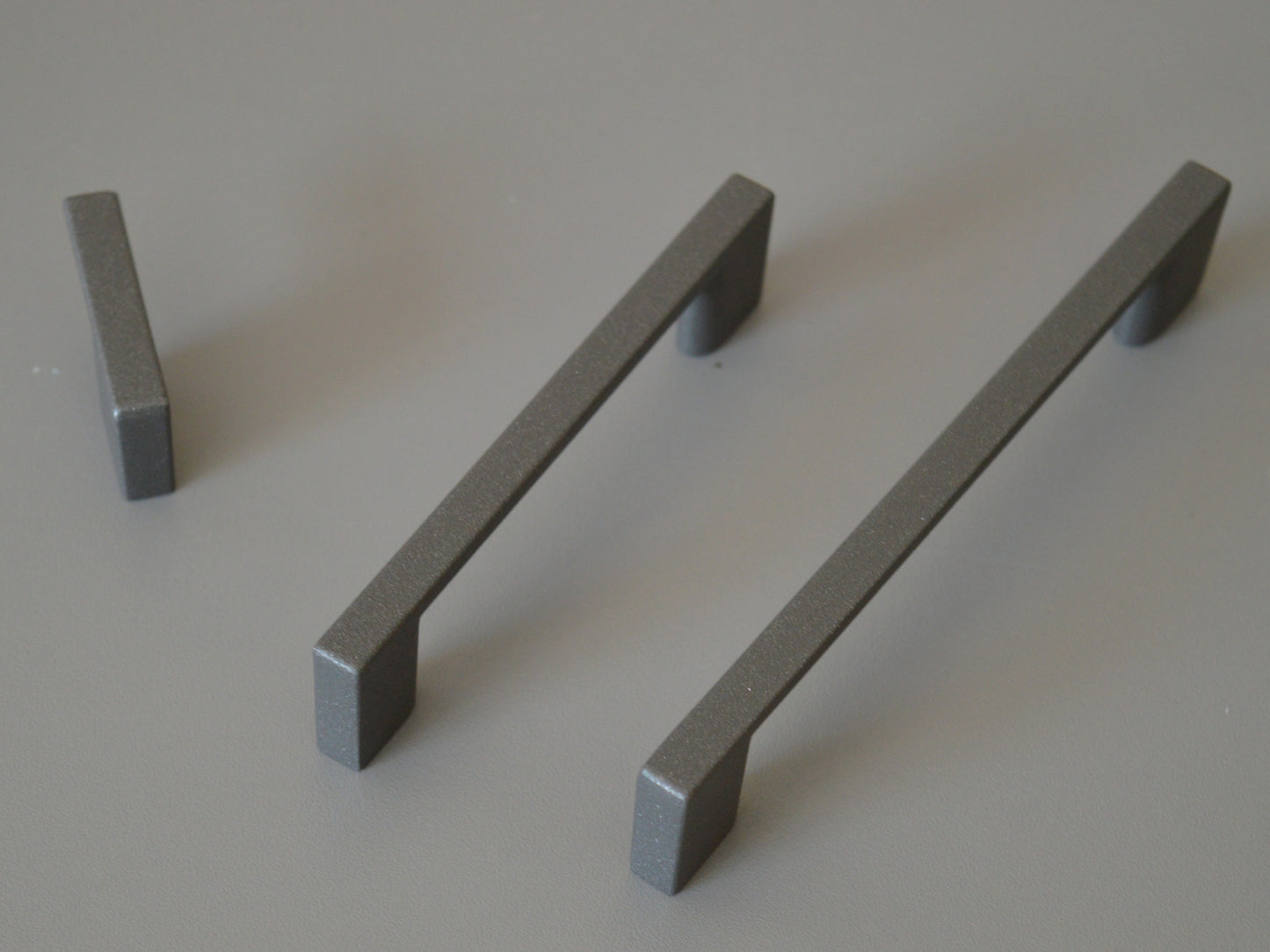 Metal furniture handle, anthracite gray color, with a unique textured surface