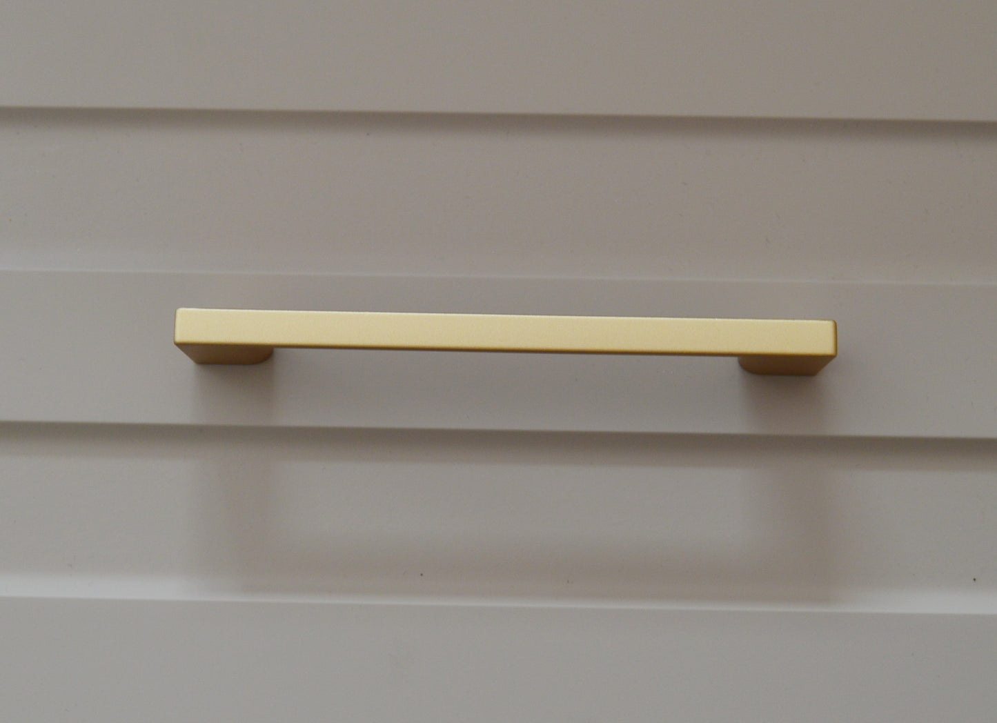 Metal furniture handle, matt gold color, with a unique textured surface
