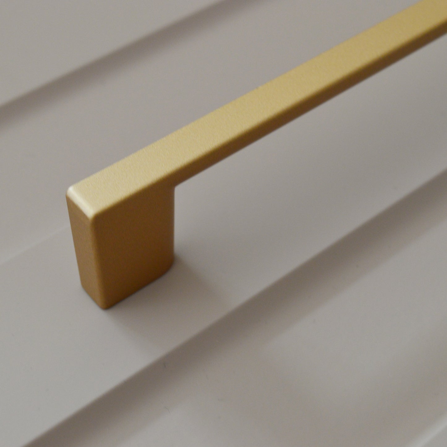 Metal furniture handle, matt gold color, with a unique textured surface