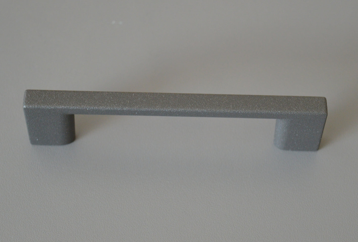 Metal furniture handle, anthracite gray color, with a unique textured surface