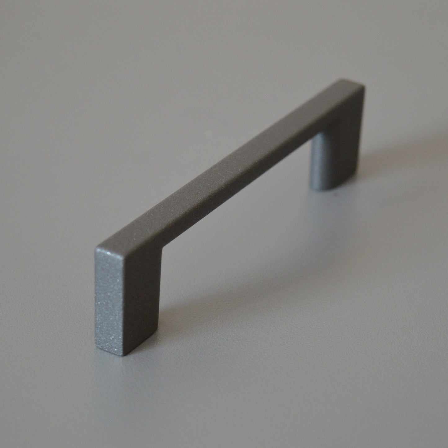 Metal furniture handle, anthracite gray color, with a unique textured surface