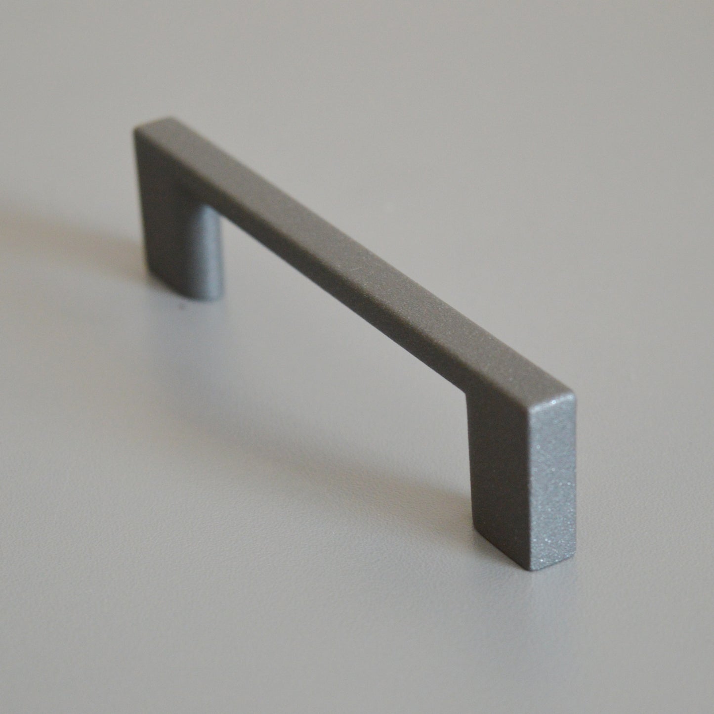 Metal furniture handle, anthracite gray color, with a unique textured surface